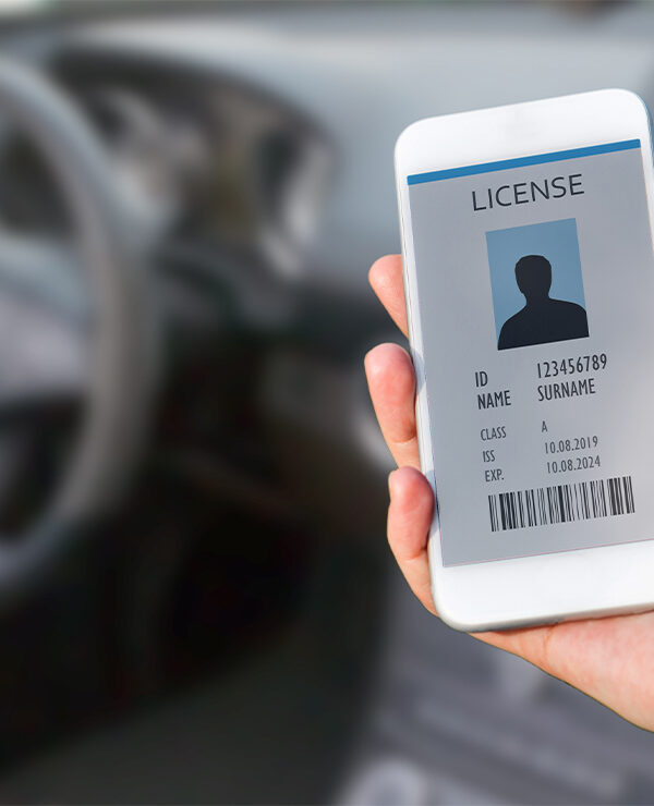 A hand (within a car) holding a cellphone displaying a digital drivers license.