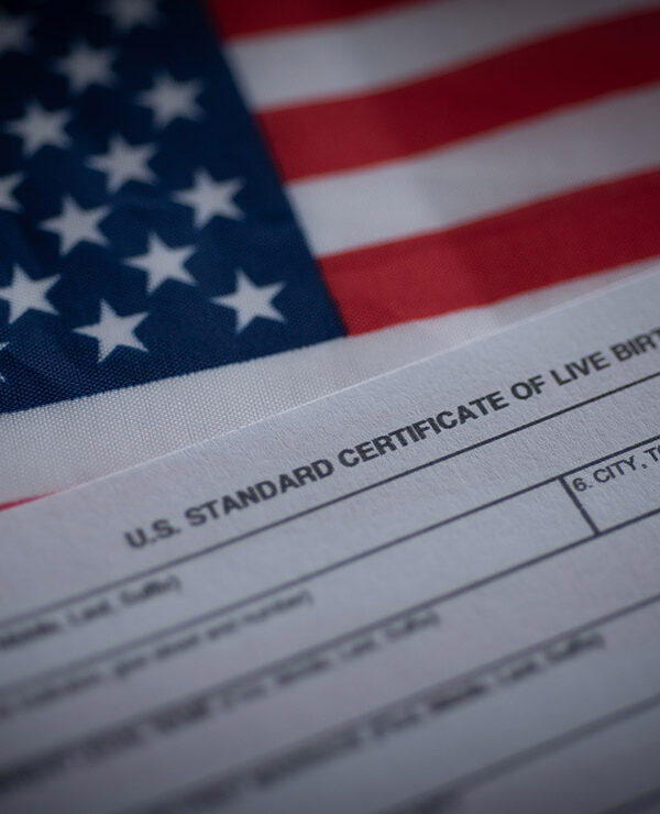 A birth certificate in front of an American flag.