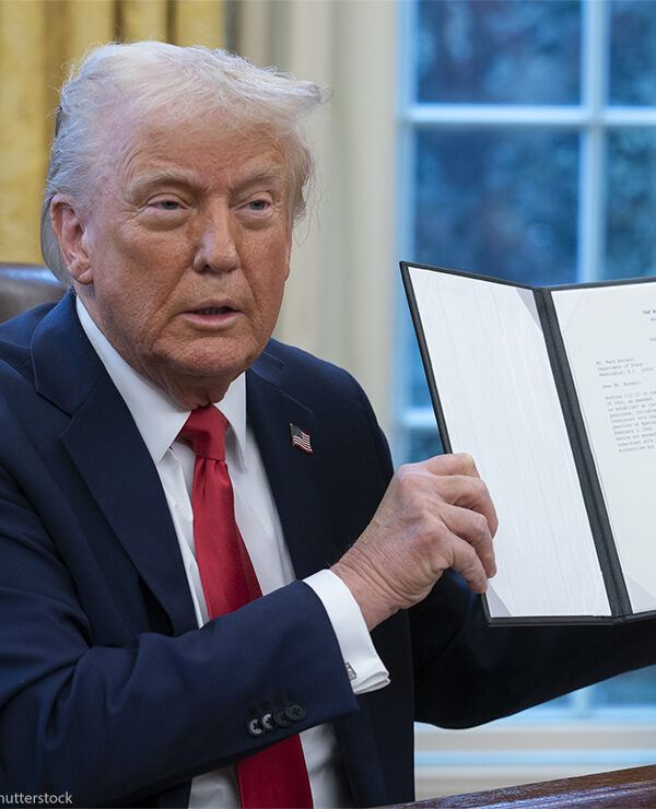 President Donald Trump holds up a recently signed executive order in the Oval Office of the White House.