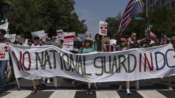 Demonstrators march in Washington, DC carrying a banner that reads " NO NATIONAL GUARD IN DC".