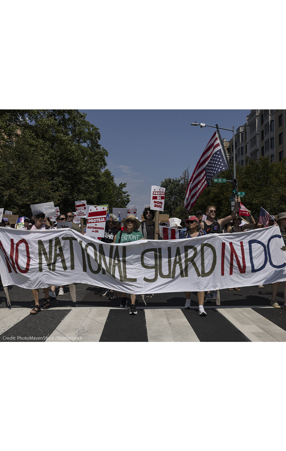 Demonstrators march in Washington, DC carrying a banner that reads " NO NATIONAL GUARD IN DC".