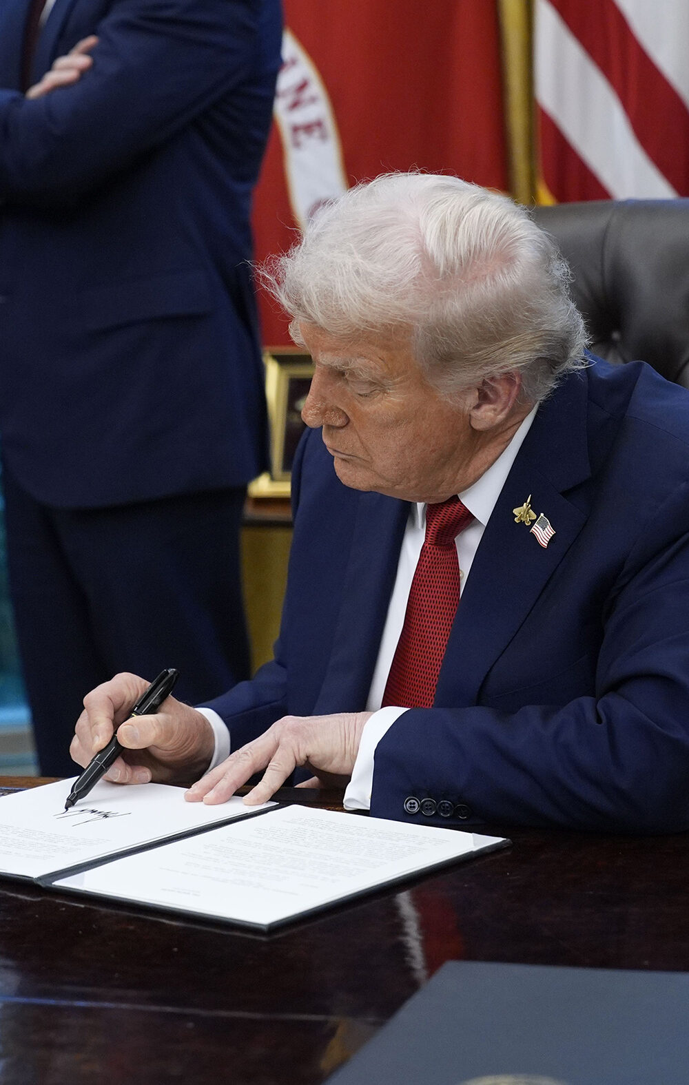 President Trump signs an executive order in the Oval Office of the White House.